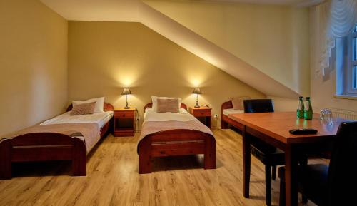 a room with two beds and a desk and a table at Bohema Restauracja i Noclegi in Supraśl