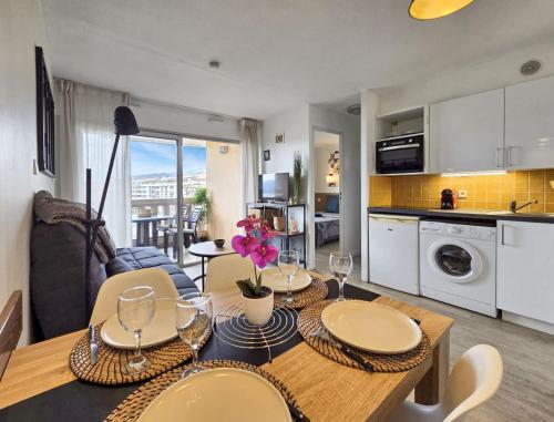 une cuisine et un salon avec une table et des chaises dans l'établissement Le Cannes Beach 468 - balcon vue mer & piscine, à Cannes