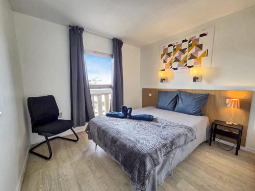 une chambre avec un lit, une chaise et une fenêtre dans l'établissement Le Cannes Beach 468 - balcon vue mer & piscine, à Cannes