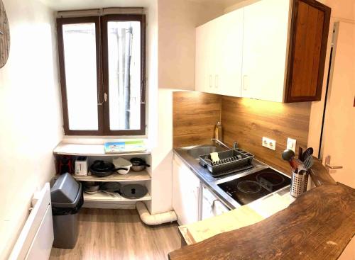 Il comprend une petite cuisine avec une cuisinière et une fenêtre. dans l'établissement Studio MAKATI, à Chambéry