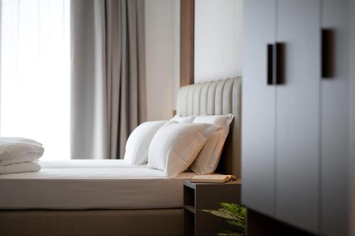 a bed with white sheets and pillows next to a window at Lumia Living Limone in Limone sul Garda