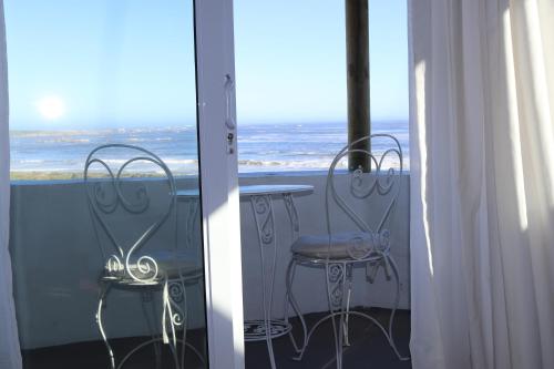 a table and chairs on a balcony with the ocean at Gilcrest Place Guest House in Paternoster
