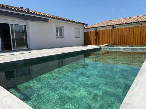 - une piscine d'eau claire en face d'une maison dans l'établissement Maison cosy avec piscine 8 pers, à Parentis-en-Born