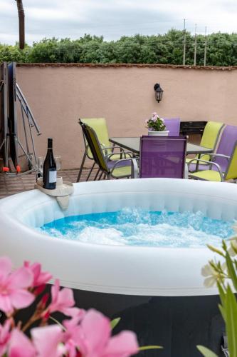 a hot tub with a bottle of wine and a table and chairs at Linett Apartman in Hajdúszoboszló