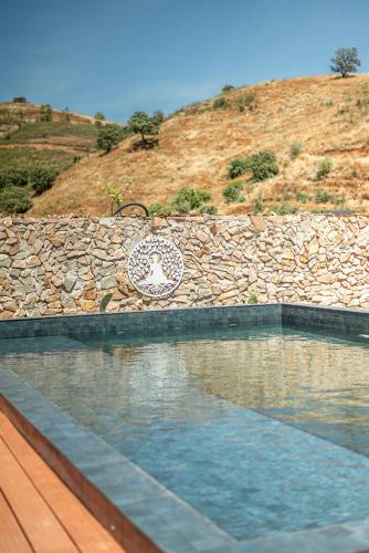 a swimming pool in front of a stone wall at Portugals Infinity - Fantástica casa de campo com vista de mar em Tavira in Tavira