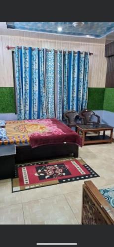 a room with a bed and a table and curtains at Shri Anand Hotel Berinag Shahgram with Parking included in Berināg