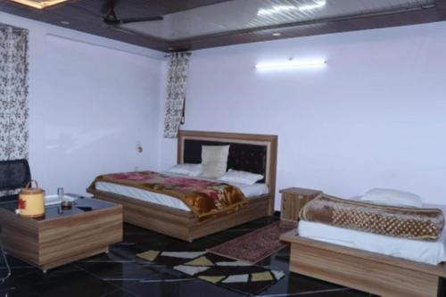 a bedroom with a bed and a table in a room at Shri Anand Hotel Berinag Shahgram with Parking included in Berināg
