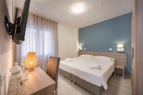 a hotel room with a bed and a desk and a television at Hotel Capinera in Caorle
