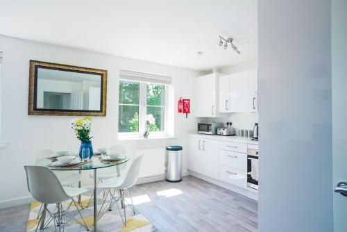 a kitchen with white cabinets and a table and chairs at Central 2 Bedroom Flat with 2 Parking Spaces, Quiet and Modern Stay in Peterborough