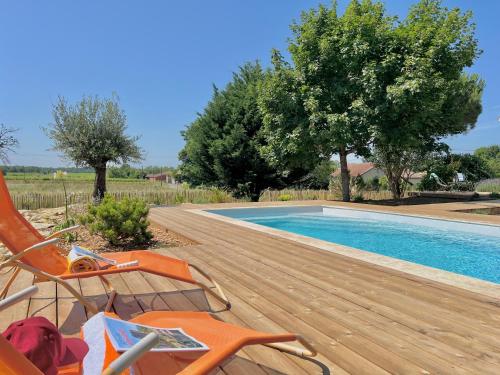 - une piscine avec une terrasse et des chaises à côté dans l'établissement Charmante maison avec piscine au cœur des vignes, à Saint-Philippe-dʼAiguille