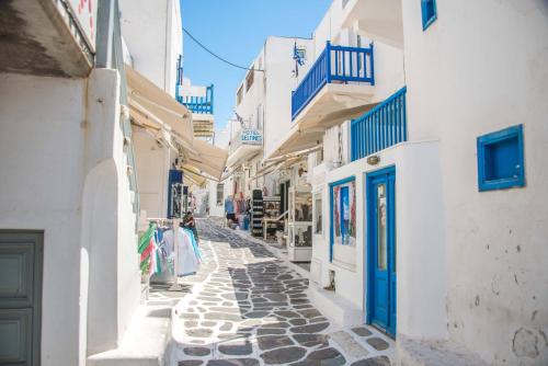 a woman walking down an alley in a town with white buildings at Hotel Delfines in Mýkonos City