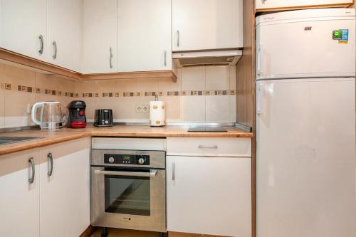 a kitchen with white cabinets and a refrigerator at Apartamento turístico mad-aeropuerto ifema in Madrid
