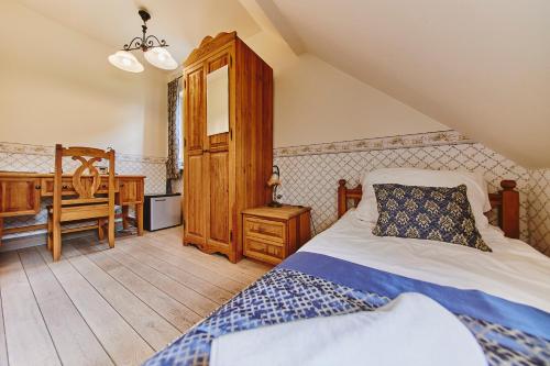 a bedroom with a bed and a desk and a chair at Folwark Hutta in Suwałki
