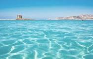 a large body of blue water with a building in the background at Appartamento Vacanze in Stintino