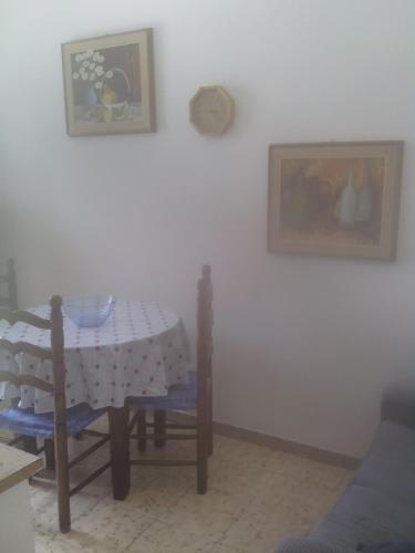 a table and chairs in a room with a white wall at Appartamento Vacanze in Stintino