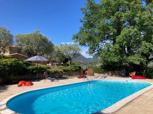 - une piscine bleue avec des chaises et un parasol dans l'établissement La Méladière, à Mirabel-aux-Baronnies