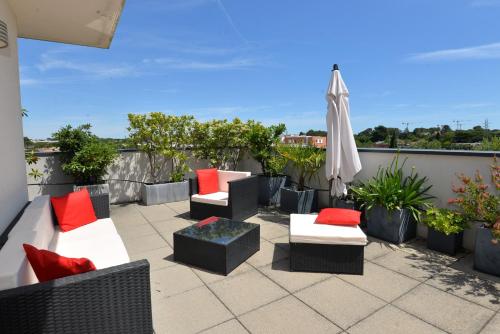 un patio avec des canapés et un parasol sur le toit dans l'établissement Luxueux Duplex avec Jacuzzi, 2 chambres, 2 Lits, à Castelnau-le-Lez