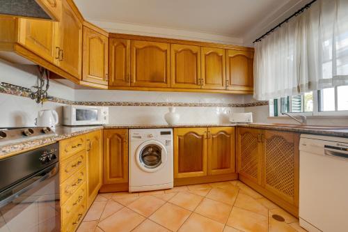 a kitchen with wooden cabinets and a washer and dryer at Muthu Clube Praia da Oura in Albufeira