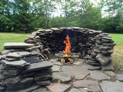 a fire pit made out of rocks in a yard at 1894 Catskills Farmhouse Retreat in Tannersville