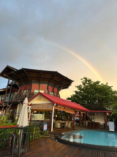 a rainbow over a building with a swimming pool at Sinurambi Cottage Rental in Penampang