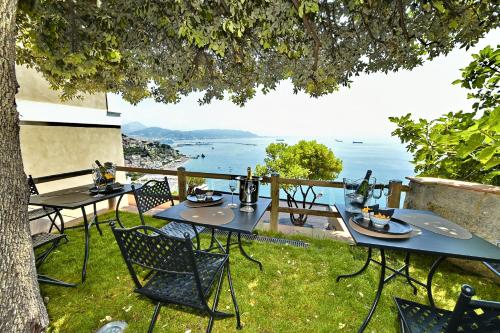 a table and chairs under a tree with a view of the ocean at In Costa Relais & Luxury Suites in Vietri sul Mare