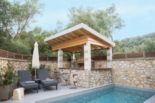 a pergola over a swimming pool next to a stone wall at September15 Suites- Meganisi in Meganisi