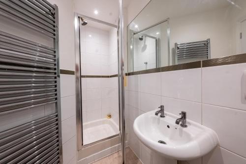 une salle de bain blanche avec lavabo et douche dans l'établissement Kingston Centre Location 2 Bed Apartment, à Kingston upon Thames