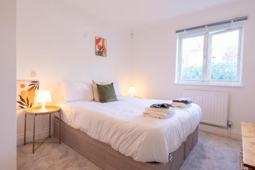 une chambre avec un lit avec des draps blancs et une fenêtre dans l'établissement Kingston Centre Location 2 Bed Apartment, à Kingston upon Thames