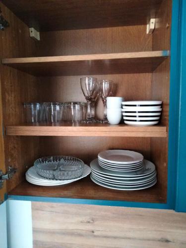 un placard avec des assiettes, des bols et des verres dans l'établissement Appartement Cosy à Nemours Hameau Chaintreauville, à Saint-Pierre-lès-Nemours