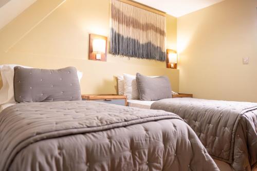 a bedroom with two beds in a room with ceilings at Hotel Cap Polonio in Ushuaia