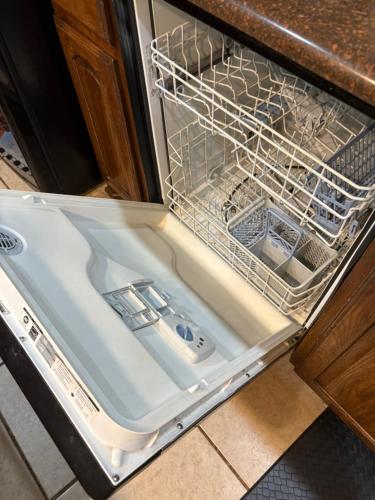 an empty dishwasher in a kitchen with its door open at Spacious 5 bedroom Retreat - Gym - Office - Games - Near PGA Frisco & Universal in Little Elm