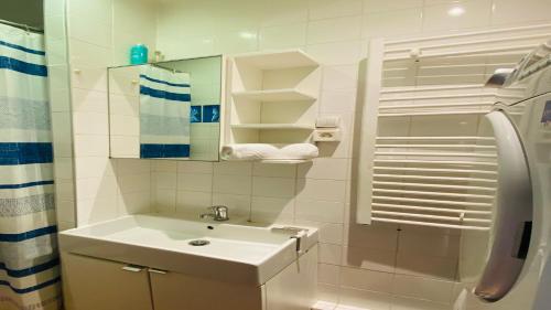une salle de bain blanche avec un lavabo et un miroir dans l'établissement Charming Apartment near The Eiffel Tower, à Paris
