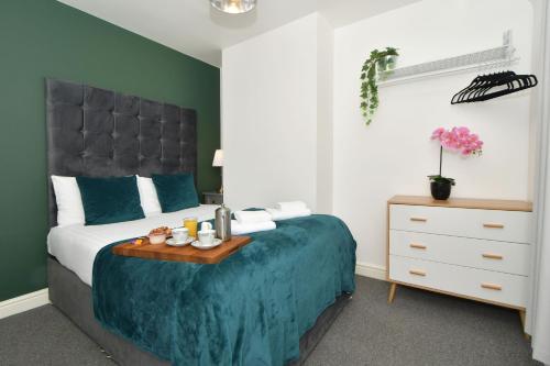 a bedroom with a bed with a blue comforter and a table at Polaris House - sleeps 6, driveway, garden in Crewe