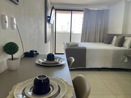 a bedroom with a bed and a table with plates on it at Manaíra Apart Hotel in João Pessoa