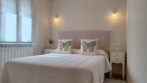 a bedroom with a white bed with butterflies on the pillows at Vivienda de Uso Turístico Los Castaños in San Román de Sanabria