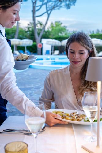 a woman sitting at a table with a plate of food at Hotel Negresco in Lido di Jesolo