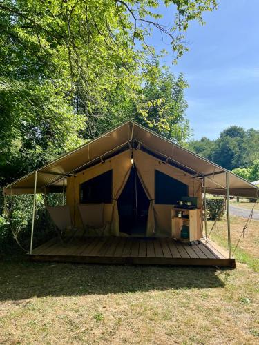 une tente avec une terrasse en bois dans un champ dans l'établissement Camping Onlycamp Le Val Joyeux, à Château-la-Vallière