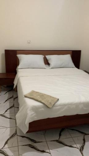 a bed with white sheets and a napkin on it at Résidence REHA in Bafoussam