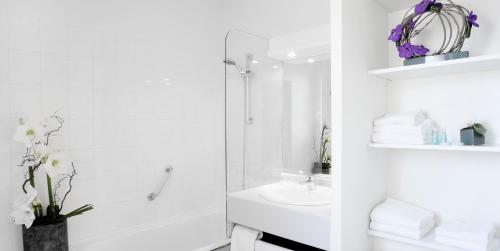 La salle de bains blanche est pourvue d'une douche et d'un lavabo. dans l'établissement At Home Appart Hotel, à Toulouse