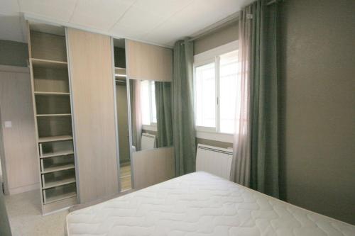 Un dormitorio con una cama blanca y un espejo grande. en Bord de mer, en Le Grau-du-Roi