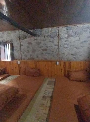 a room with a stone wall and a room with beds at Triệu hoan homestay nhà sàn cổ in Dam Thuy