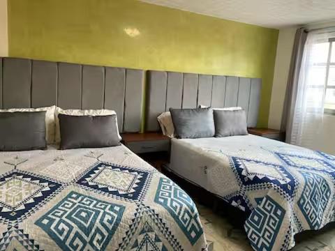 two beds sitting next to each other in a bedroom at Suites Incoreli in Pachuca de Soto