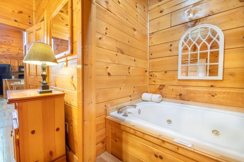 een badkamer met een bad in een houten muur bij Roudy’s Roost By Avada Properties in Pigeon Forge
