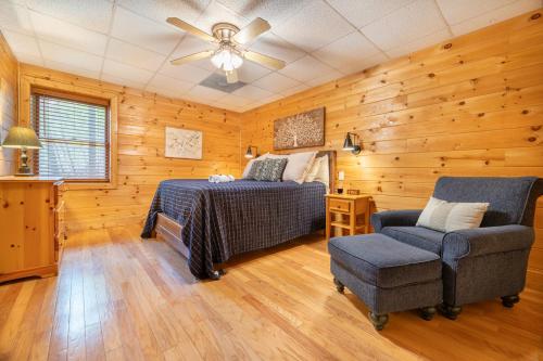 een slaapkamer met een bed en een stoel en een plafondventilator bij Roudy’s Roost By Avada Properties in Pigeon Forge