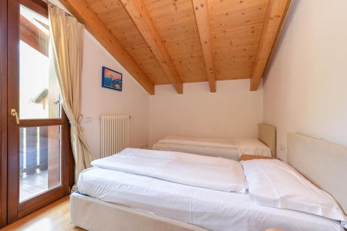 two beds in a room with a wooden ceiling at Residence Rta La Rosa delle Dolomiti in Carisolo