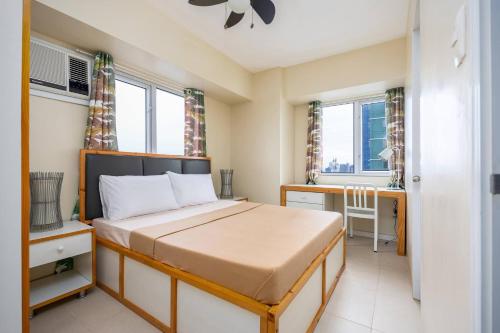 a bedroom with a bed and a desk and windows at 2-Bedroom Retreat in Avida Riala Prime Location in Cebu City