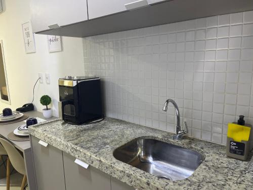 a kitchen counter with a sink and a microwave at Manaíra Apart Hotel in João Pessoa