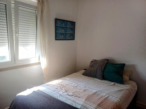 a small bedroom with a bed with a window at Amoreira Room I and II in Lisbon