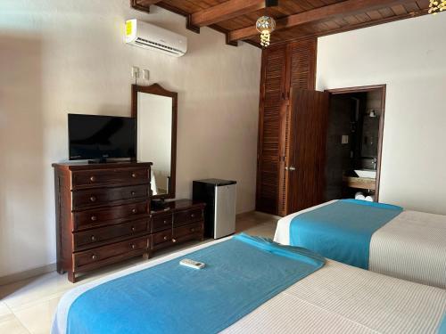 a bedroom with two beds and a dresser with a television at Club Cenotes Tulum in Balcheil
