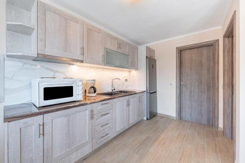 a kitchen with white cabinets and a microwave at Alex bar apartments in Sarakiniko